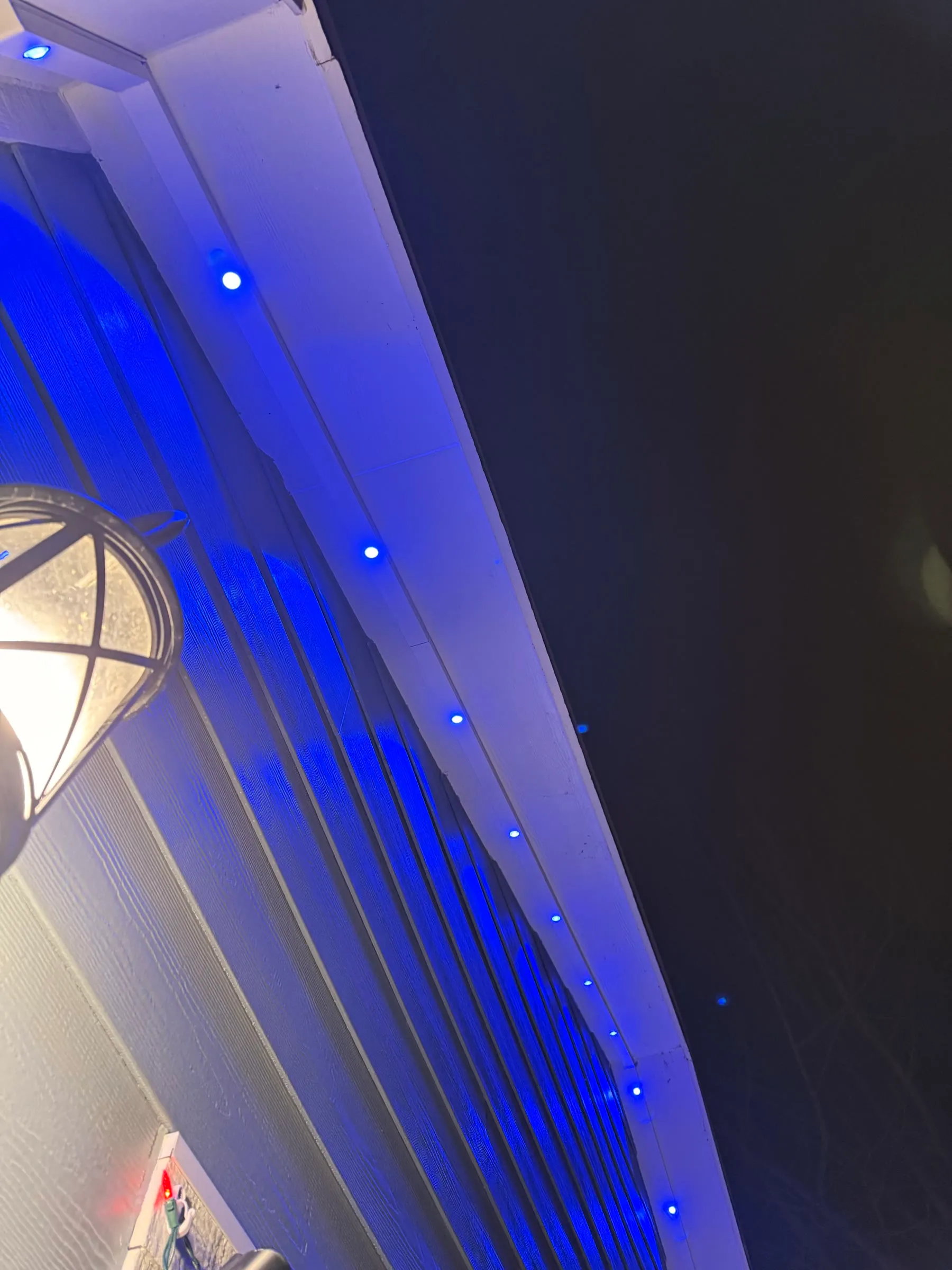 Permanent lights glowing blue along an eave at night